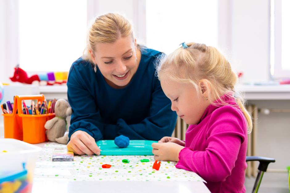 SkyClimb Method, occupational therapist working with young blonde girl doing therapeutic play activities at table with colorful materials